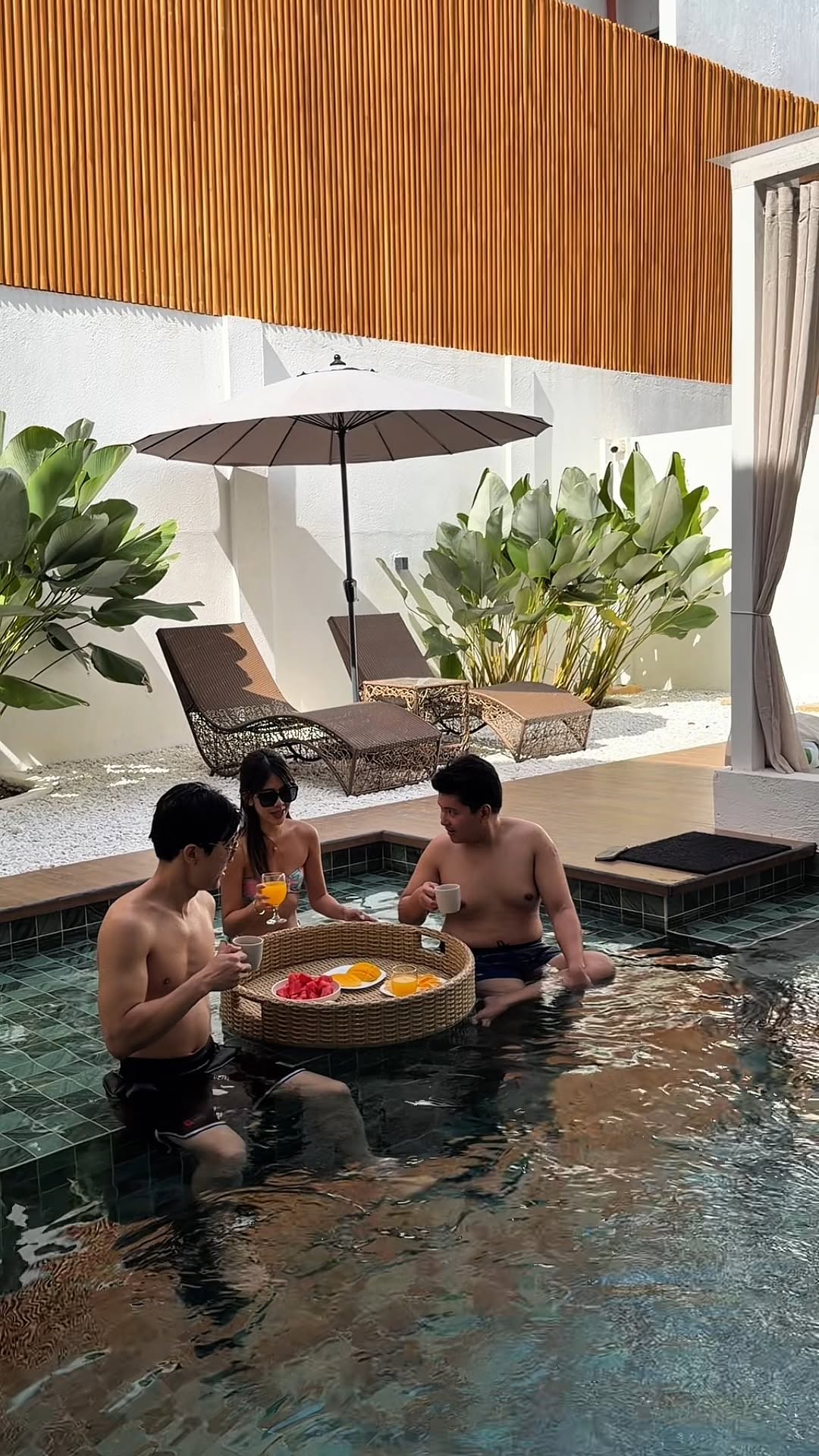 Guests enjoying the Villa Kali pool with a floating fruit tray and rattan loungers