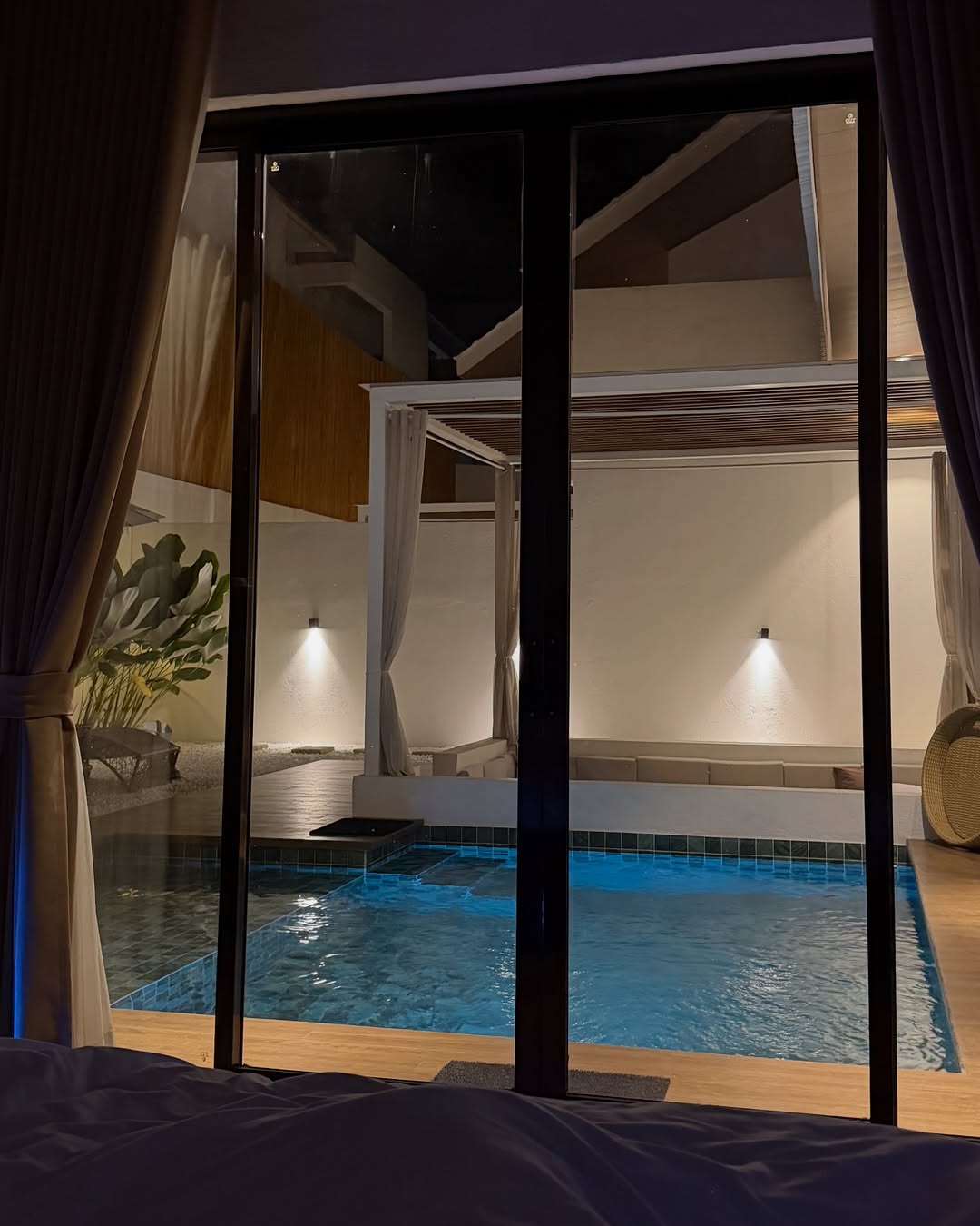 Ayatana Sea Villas — private pool glowing blue at night, seen through bedroom glass doors