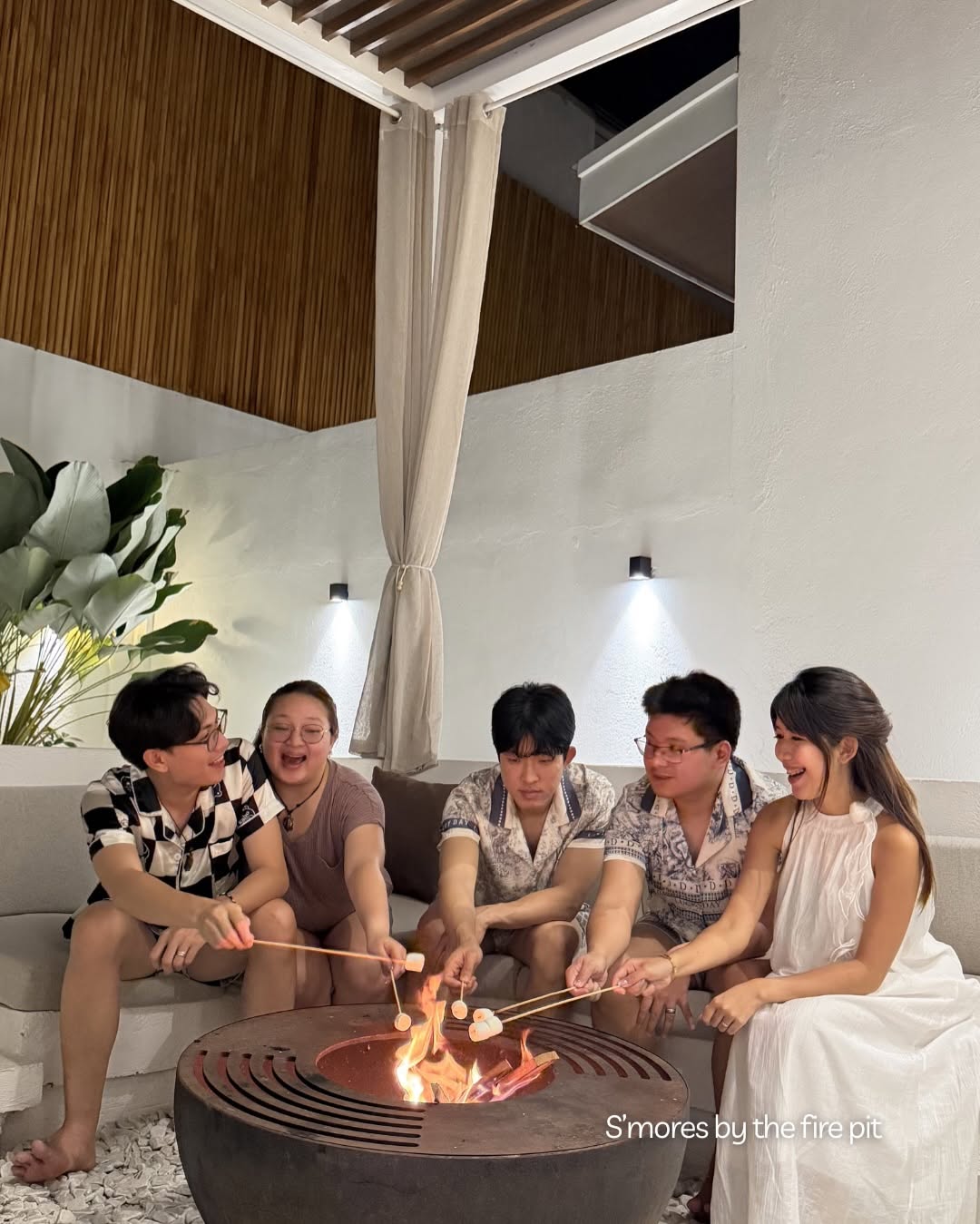Five guests roasting s'mores around the outdoor fire pit at night