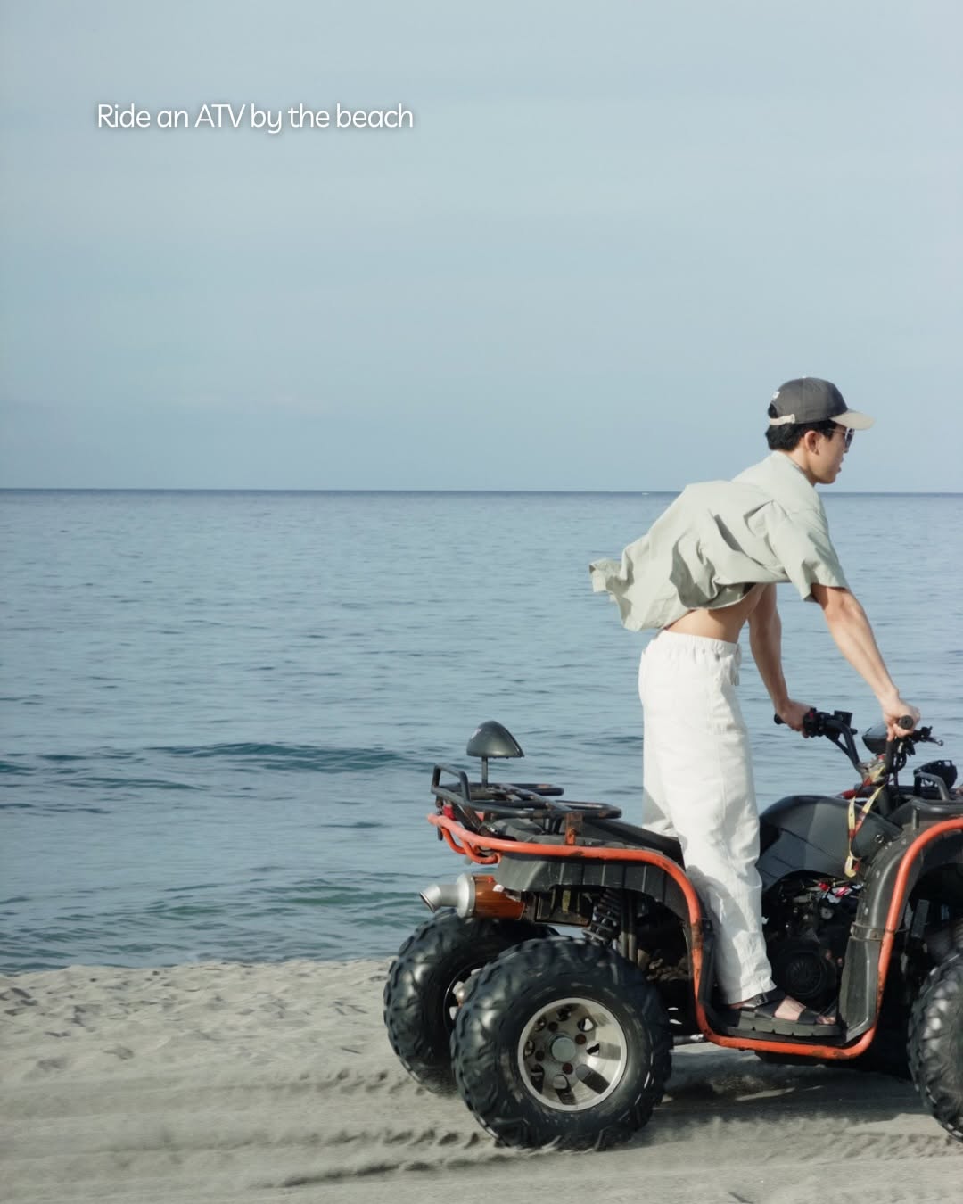 Guest riding an ATV along the beach with the clear blue sea in the background